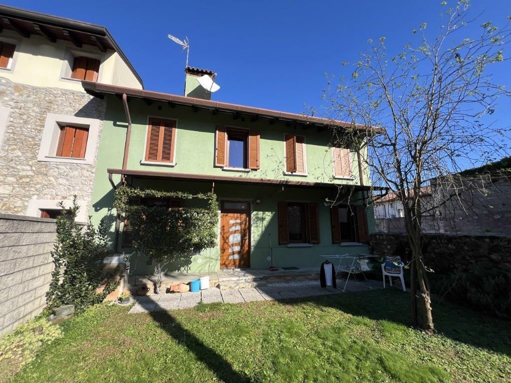 Una casa verde con le persiane marroni è circondata da un rigoglioso cortile verde.