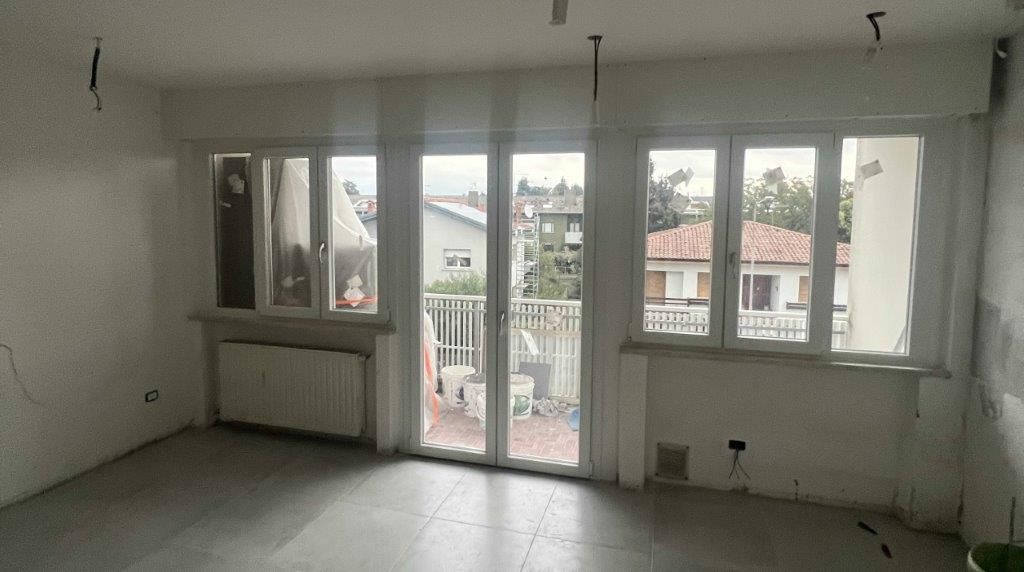 Una stanza vuota con molte finestre e un balcone.