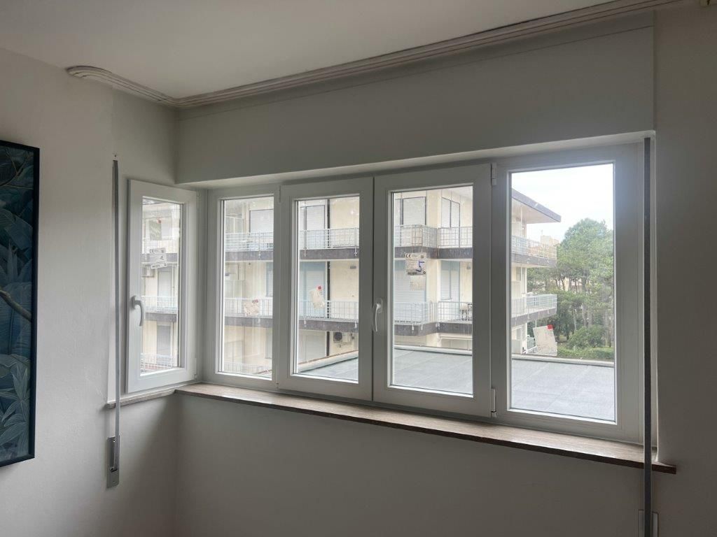 Una stanza con molte finestre e un dipinto sul muro.