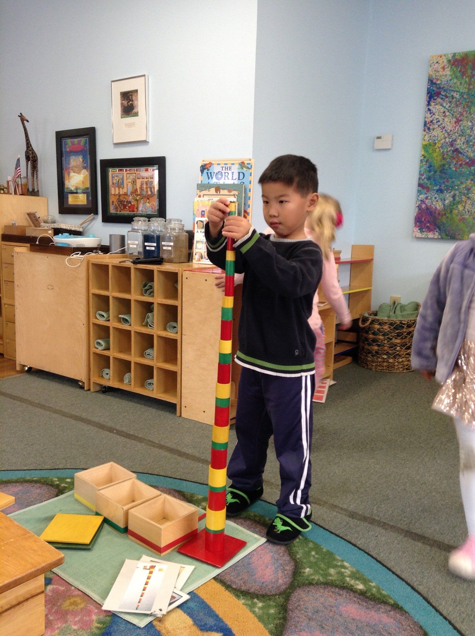 Montessori child building a tower of colorful blocks in a classroom.