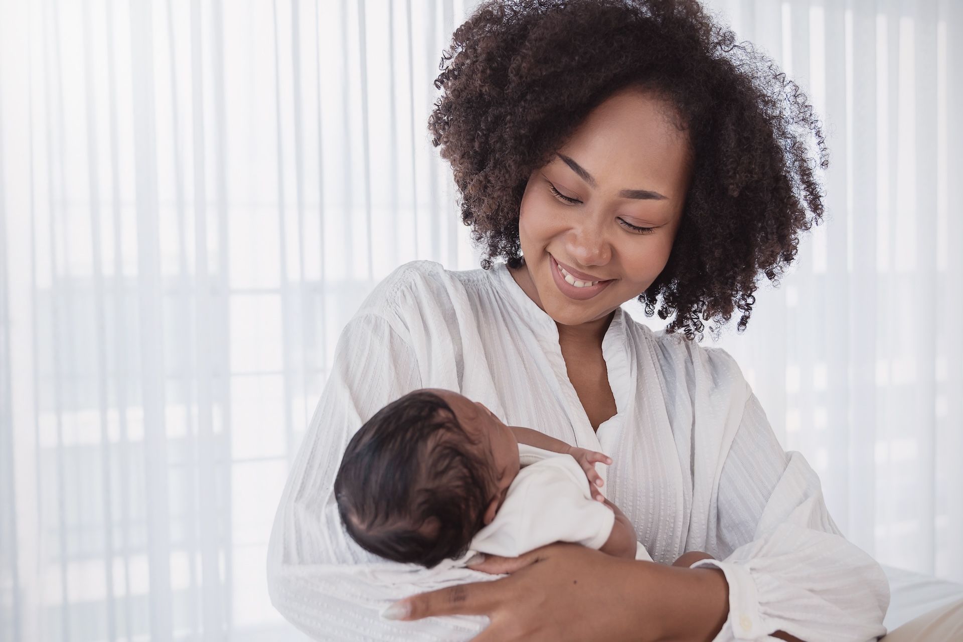 Montessori guide holding and smiling at a sleeping infant.