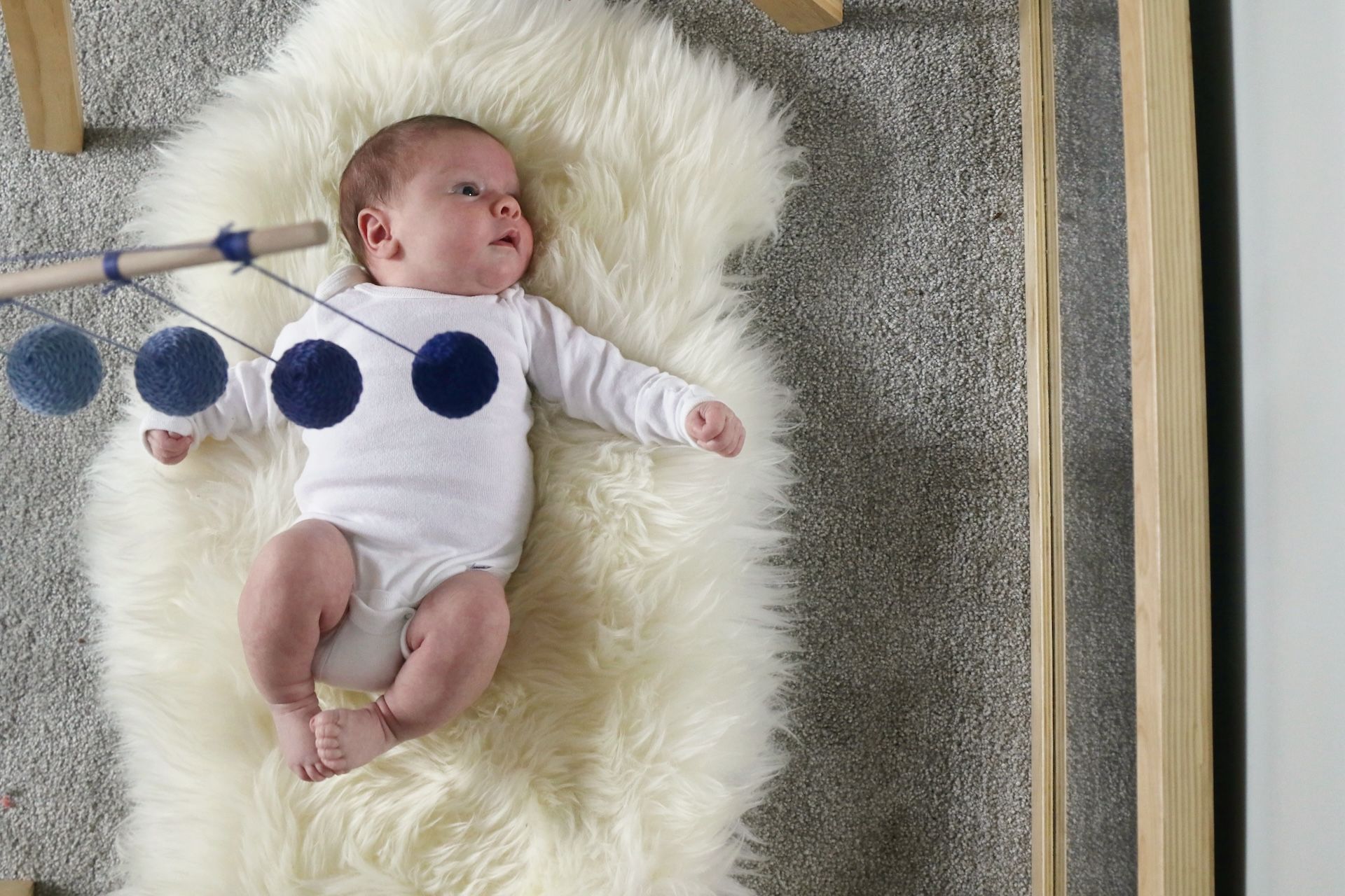 A baby is laying on a white blanket on the floor.