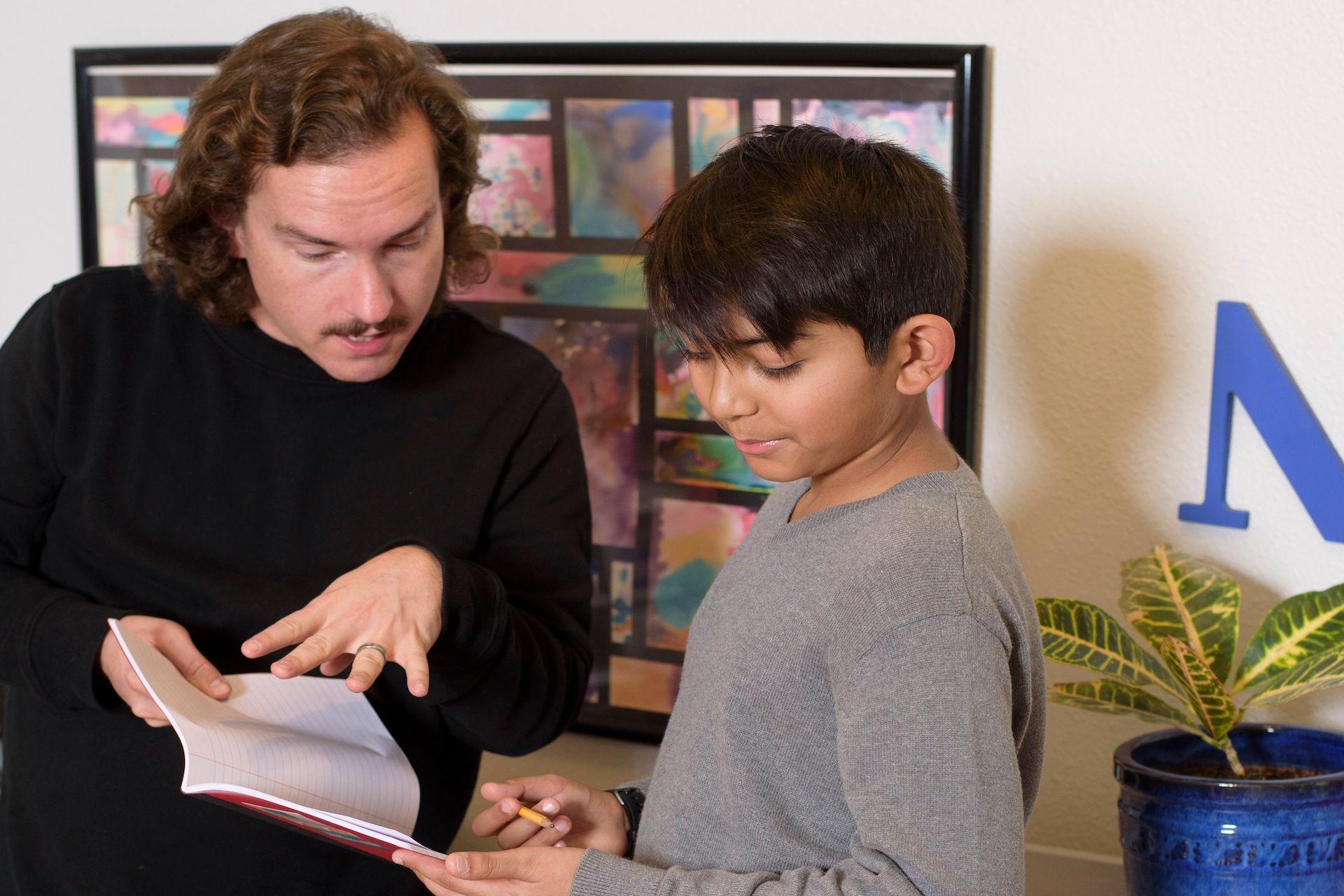A montessori guide and a student are looking at a book together