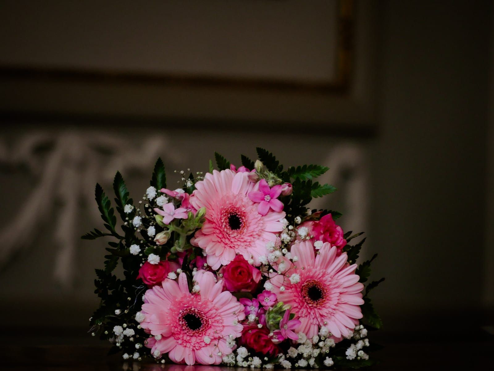 Op een tafel staat een boeket roze bloemen.