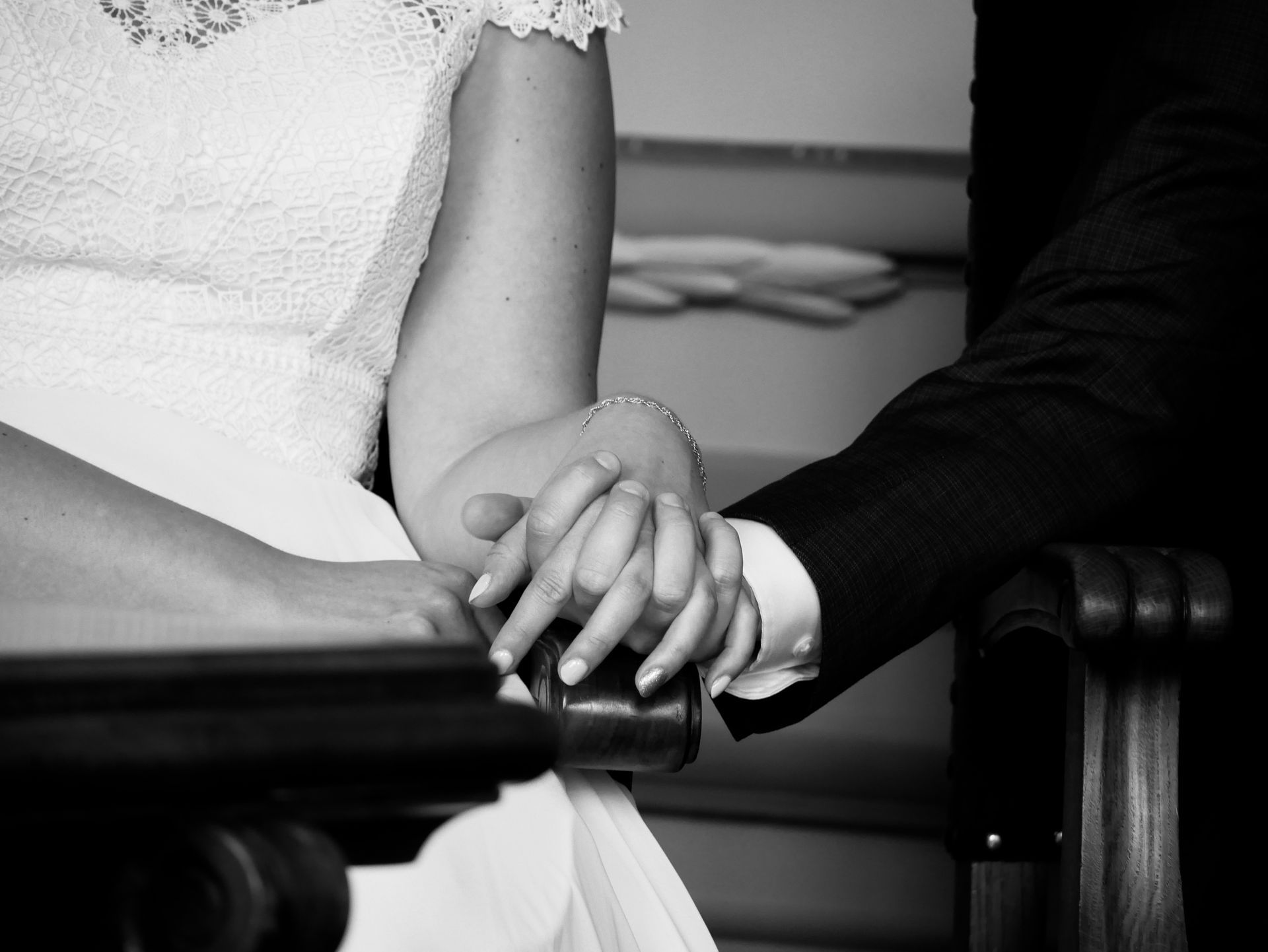 Een zwart-witfoto van een bruid en bruidegom die elkaars hand vasthouden