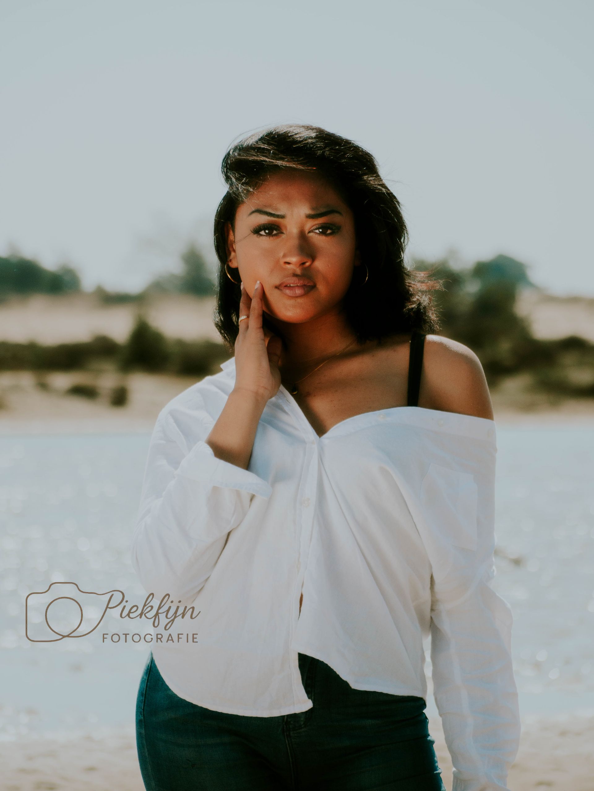 Een vrouw in een wit shirt staat op het strand.