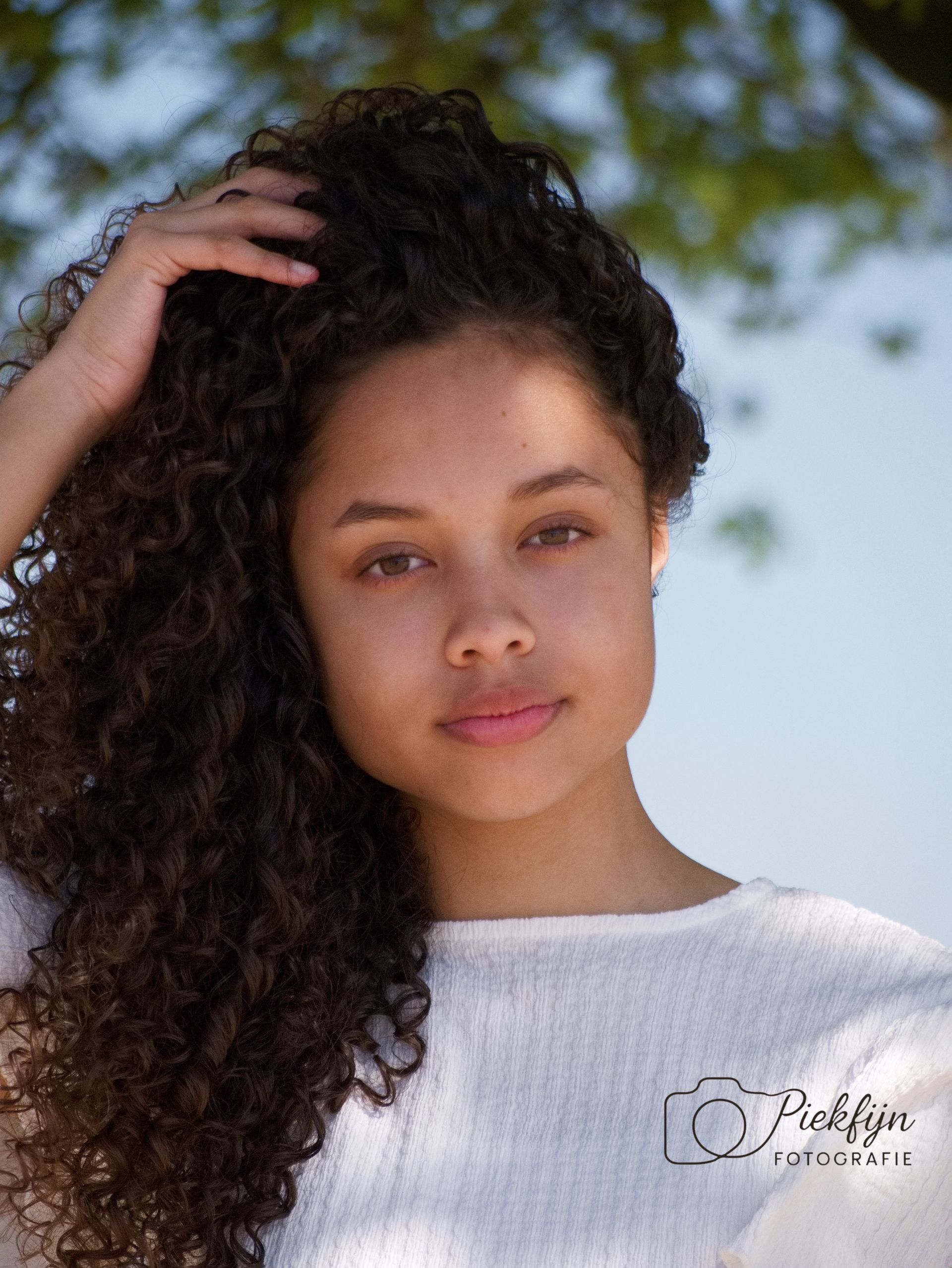 Een vrouw met krullend haar draagt een trui en lacht.