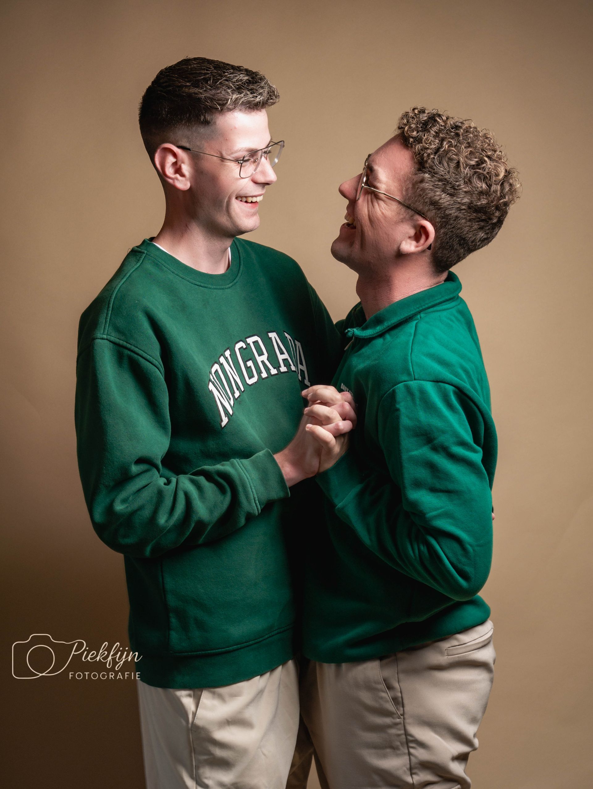 Een moeder en dochter omhelzen elkaar voor een bruine achtergrond.