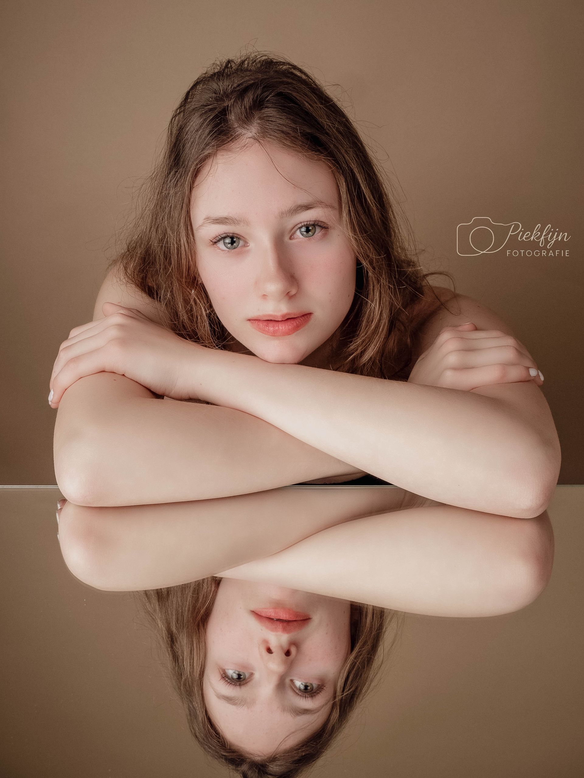 Een moeder en dochter omhelzen elkaar voor een bruine achtergrond.