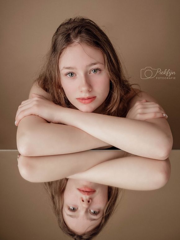 Een moeder en dochter omhelzen elkaar voor een bruine achtergrond.