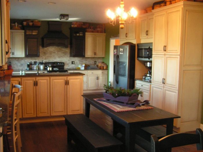 Kitchen with light cabinets, dark countertops, a black table and benches, and a black refrigerator.
