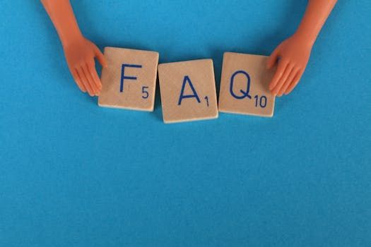 Une personne tient des tuiles de Scrabble qui épellent le mot faq.
