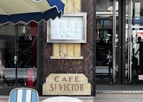 Un restaurant avec des tables et des chaises à l'extérieur et un panneau indiquant café st victor.