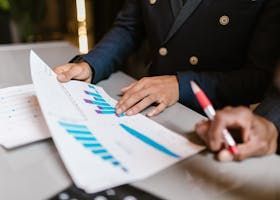 A man is sitting at a table looking at a graph.