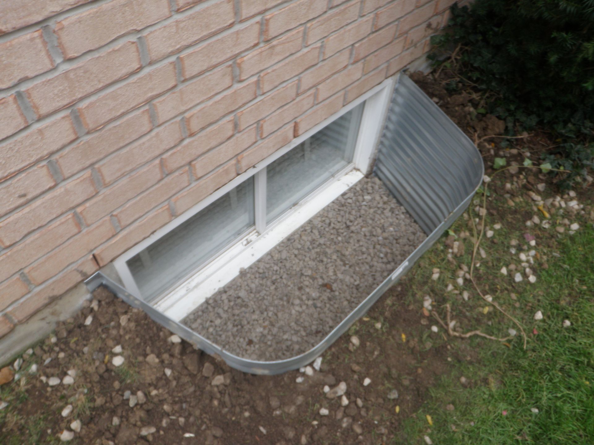 A window well on the side of a brick building.