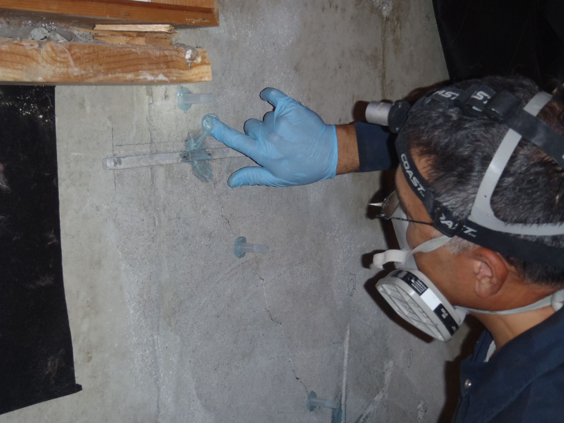 A man wearing a mask and gloves points at something on a wall