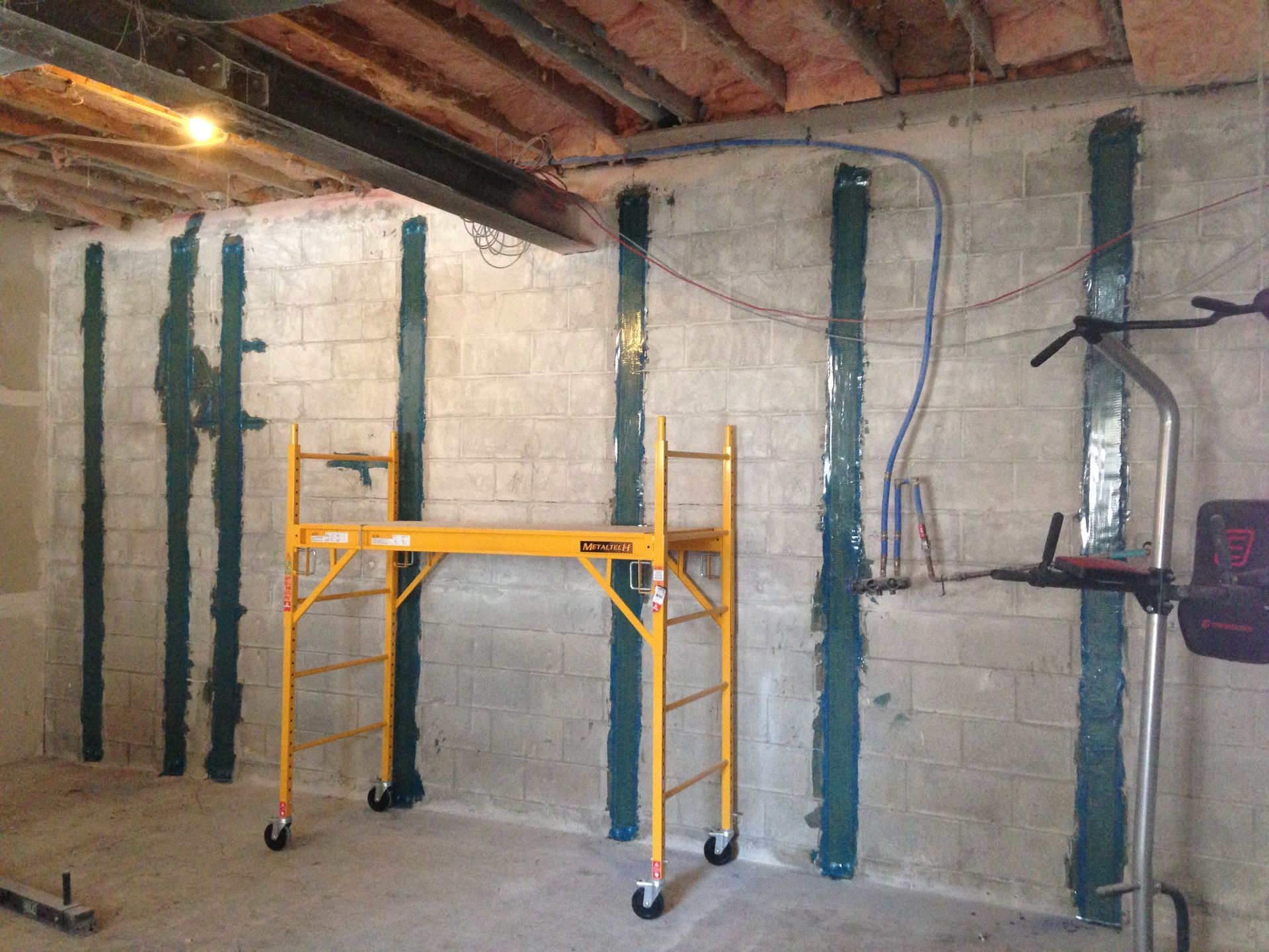 A yellow scaffolding is sitting in a room with brick walls.