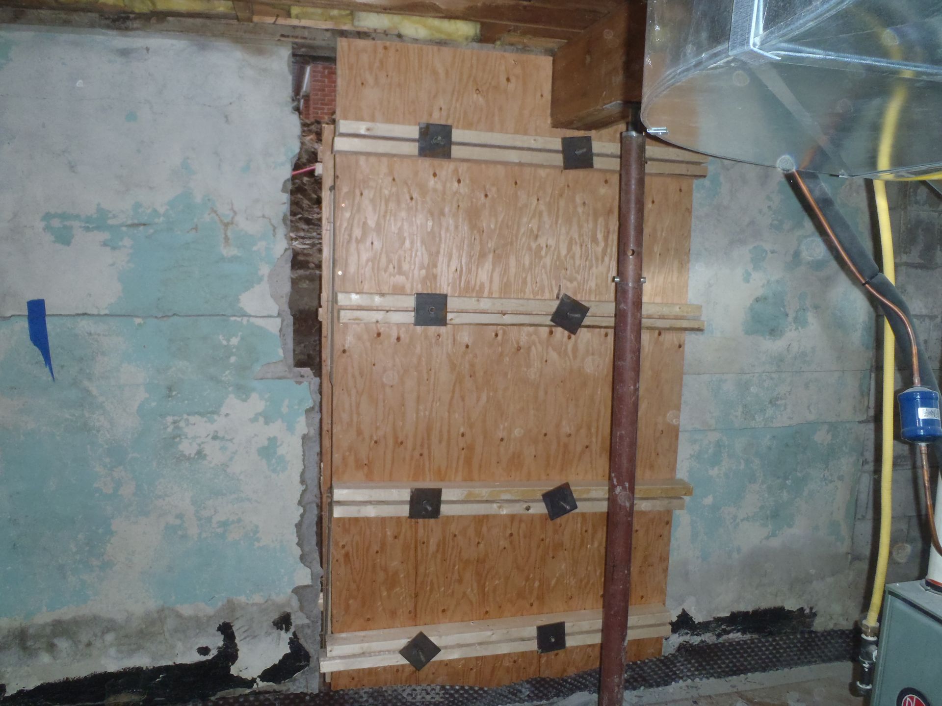 A wall in a basement is being remodeled with plywood.