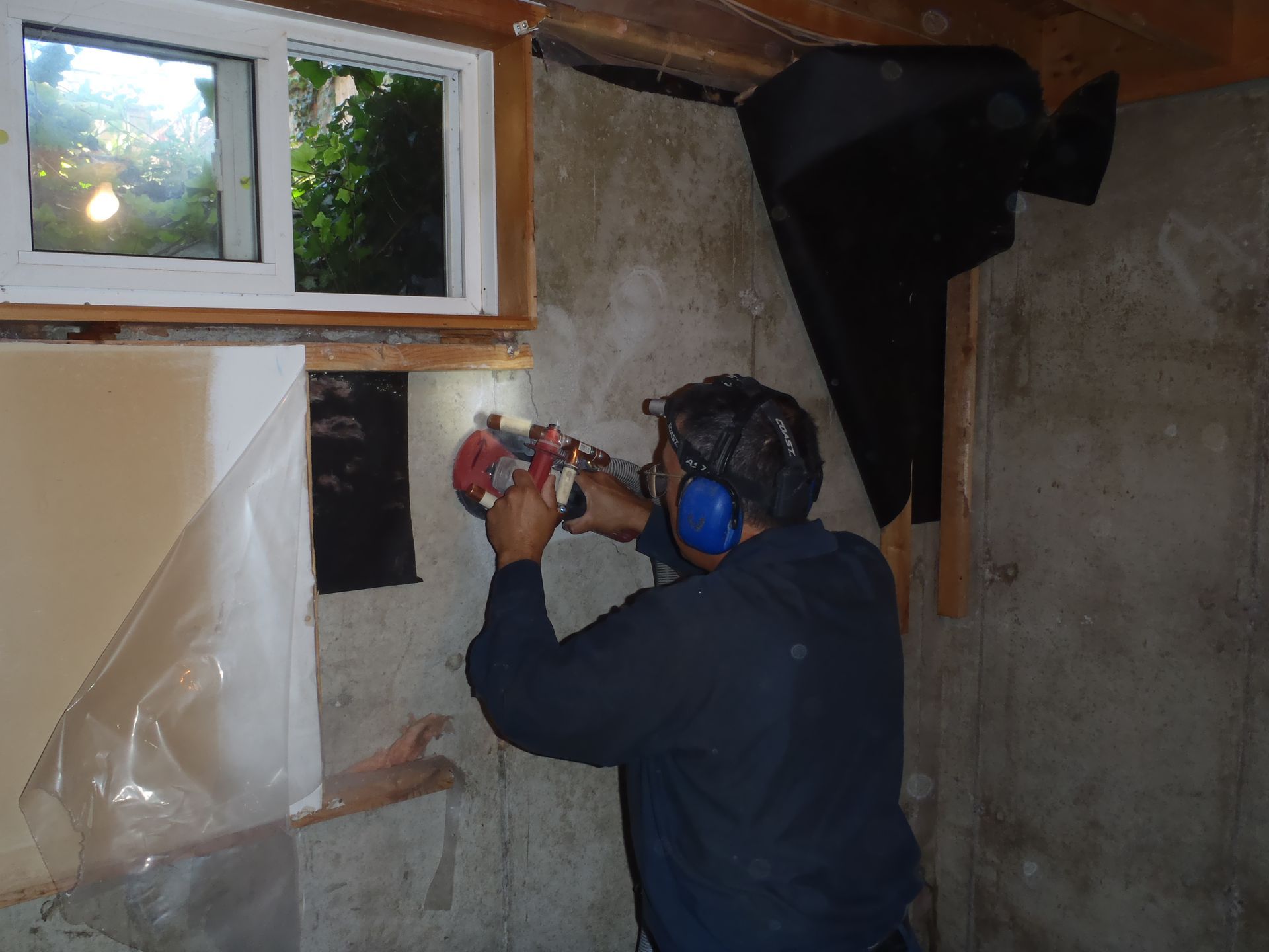 A man wearing headphones is working on a wall