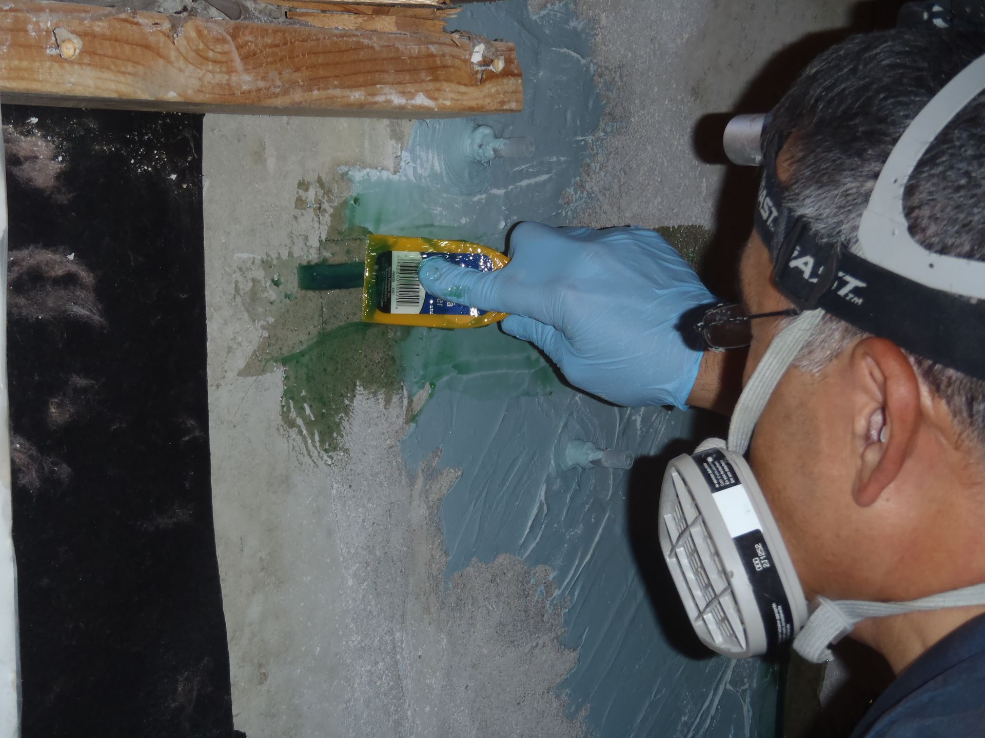 A man wearing a mask and gloves is spreading epoxy over a carbon fiber stitch