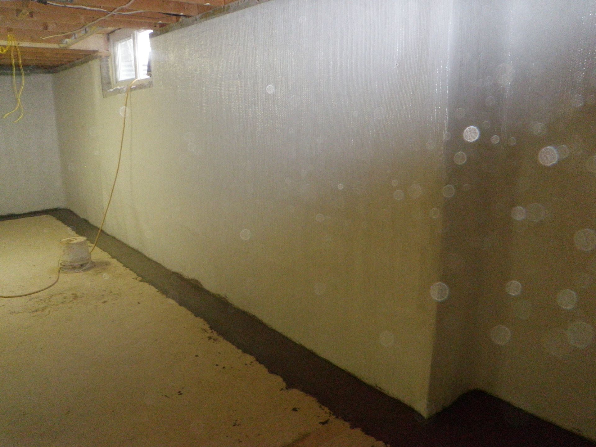 A basement with a white wall and a window.