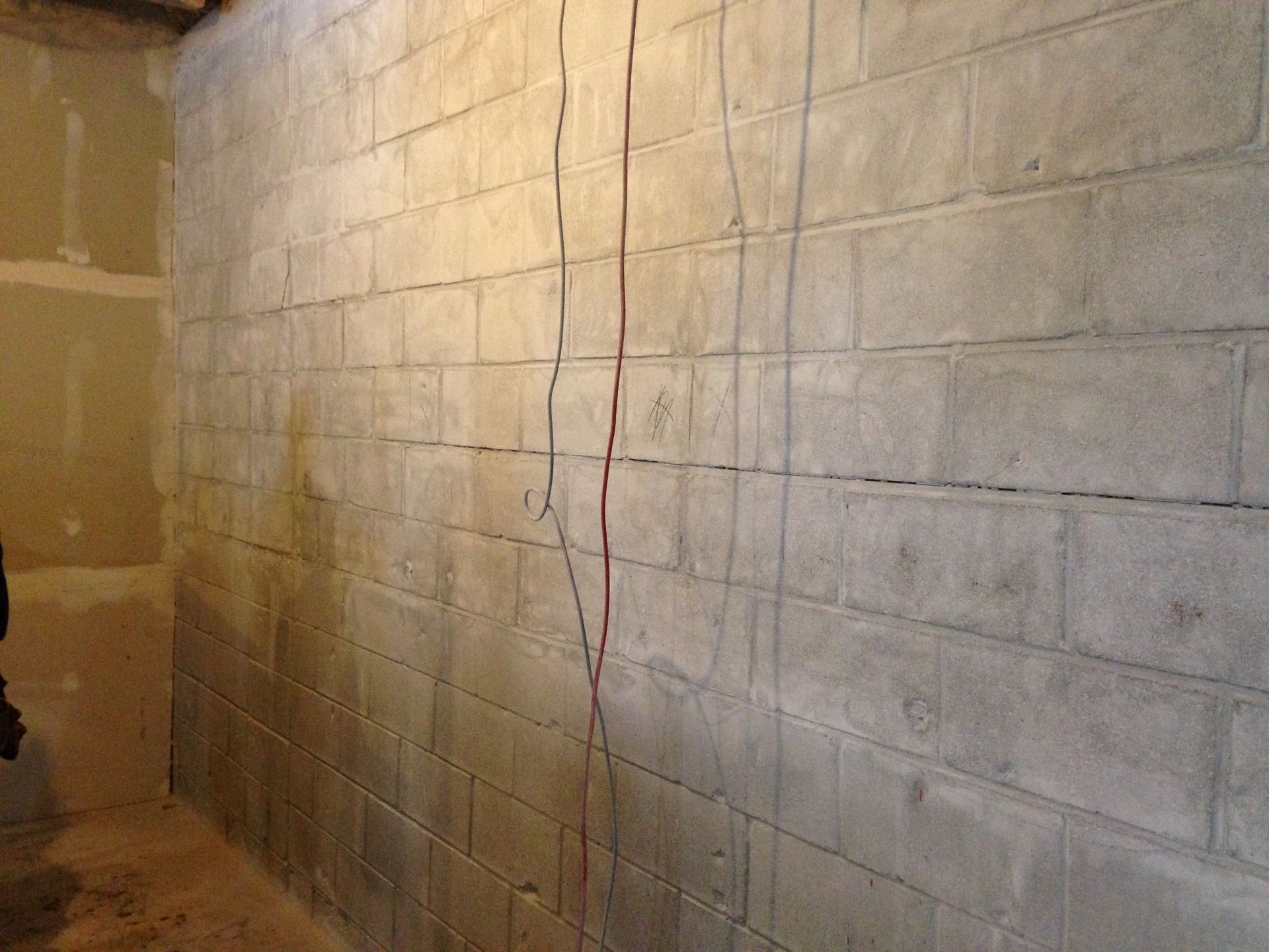 A brick wall in a room with a red cord hanging from it.