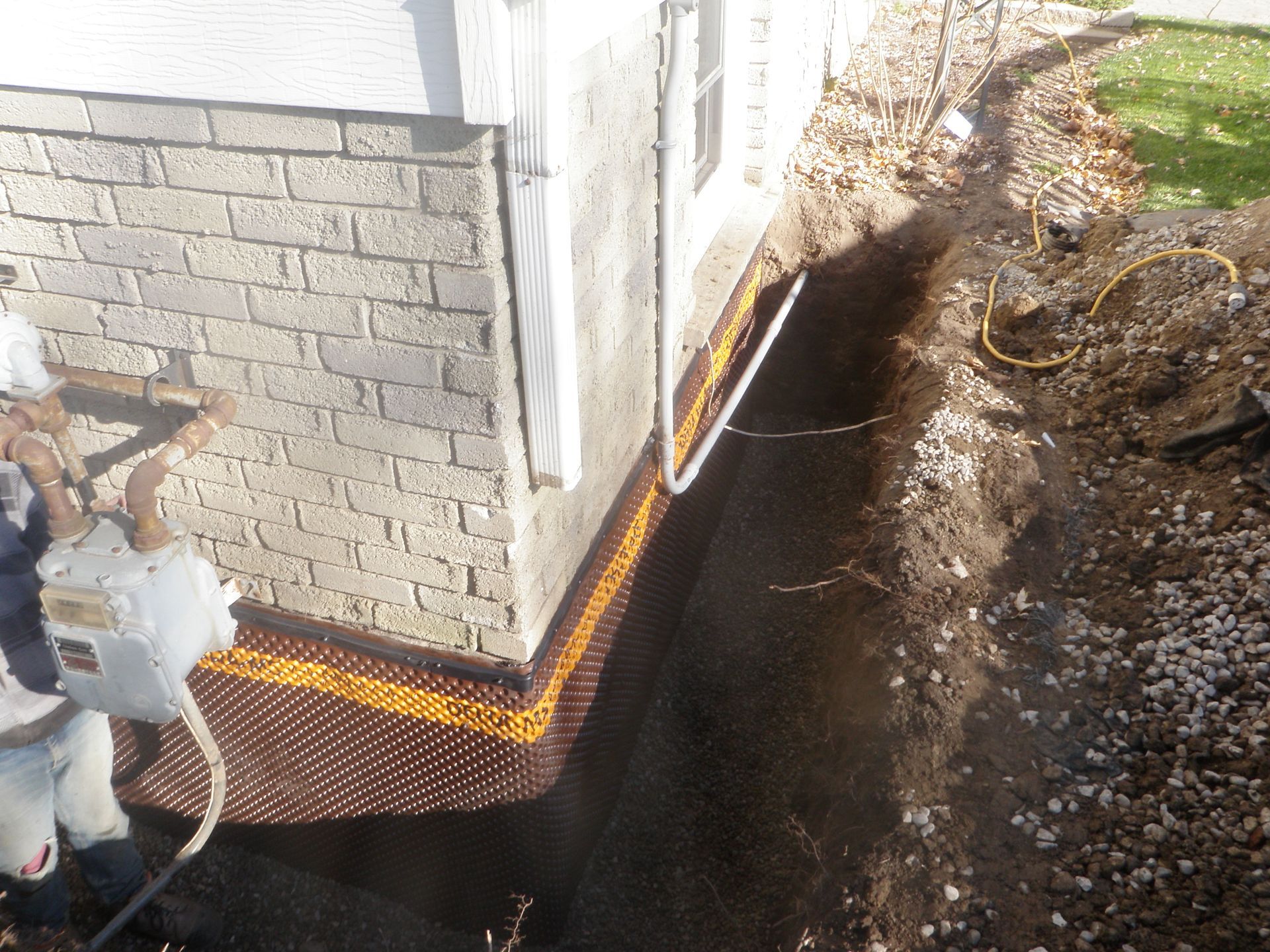 A man wearing a hard hat is working on the side of a house