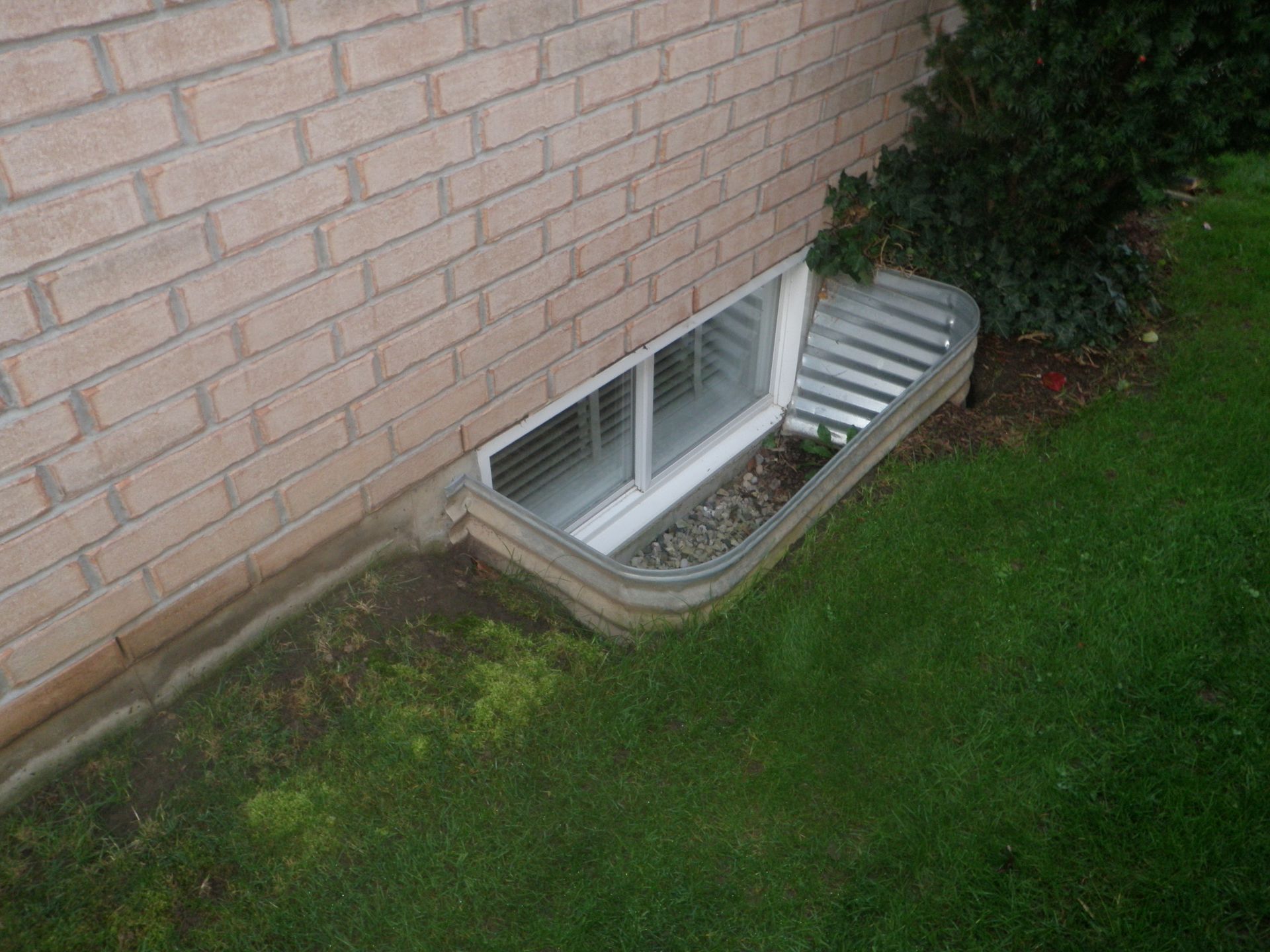 A brick wall with a window in the basement.