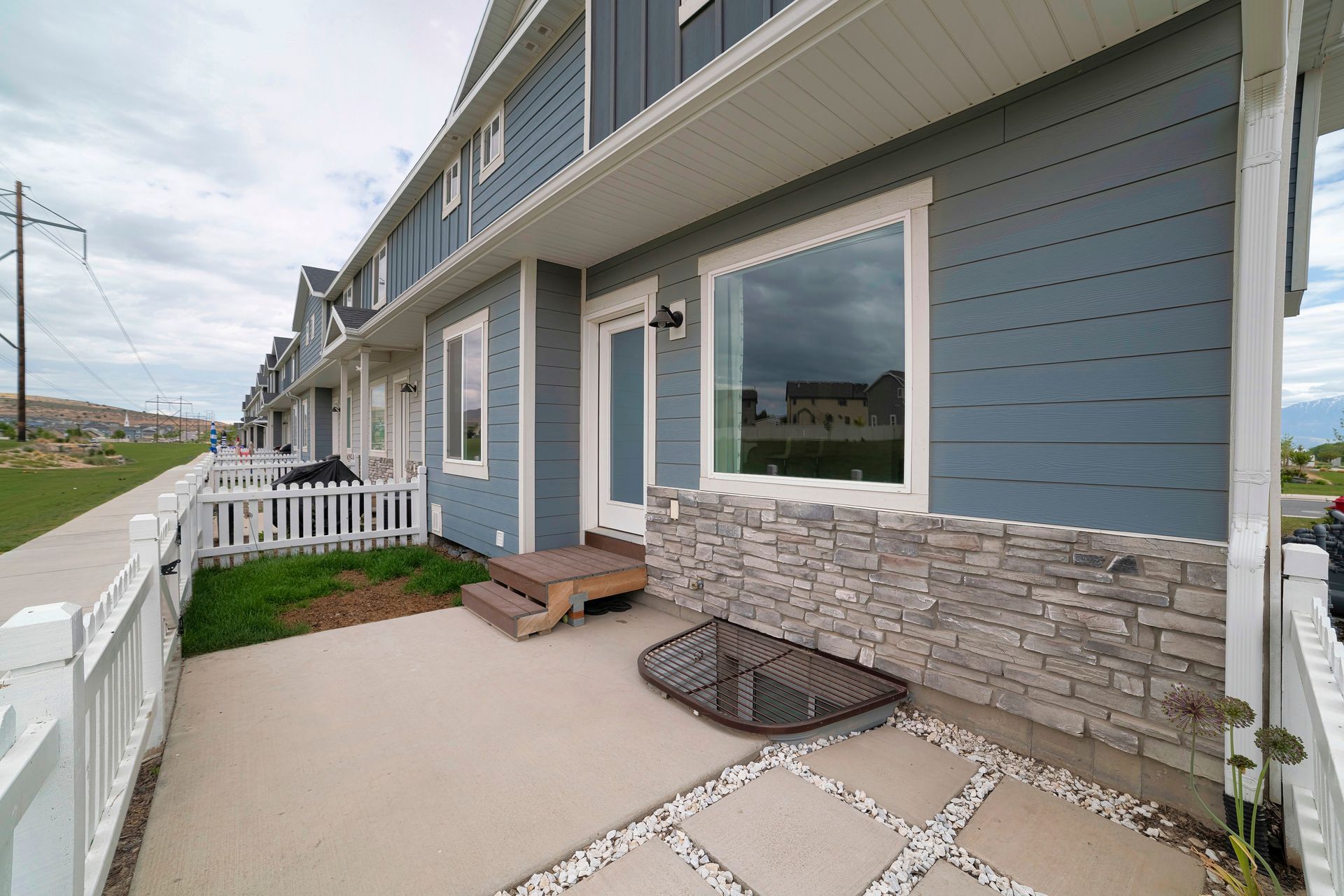 A blue house with a white fence and a patio in front of it.