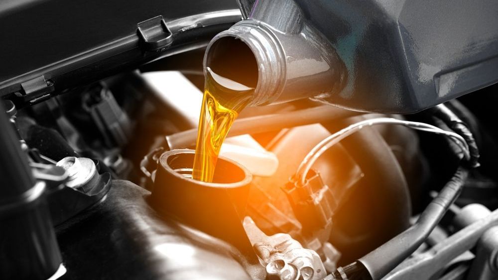 Motor oil being poured into a car engine, orange glow.