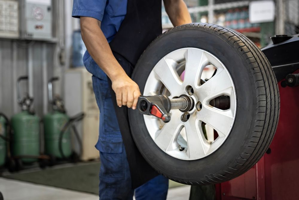 Person balancing a tire on a machine in a garage.