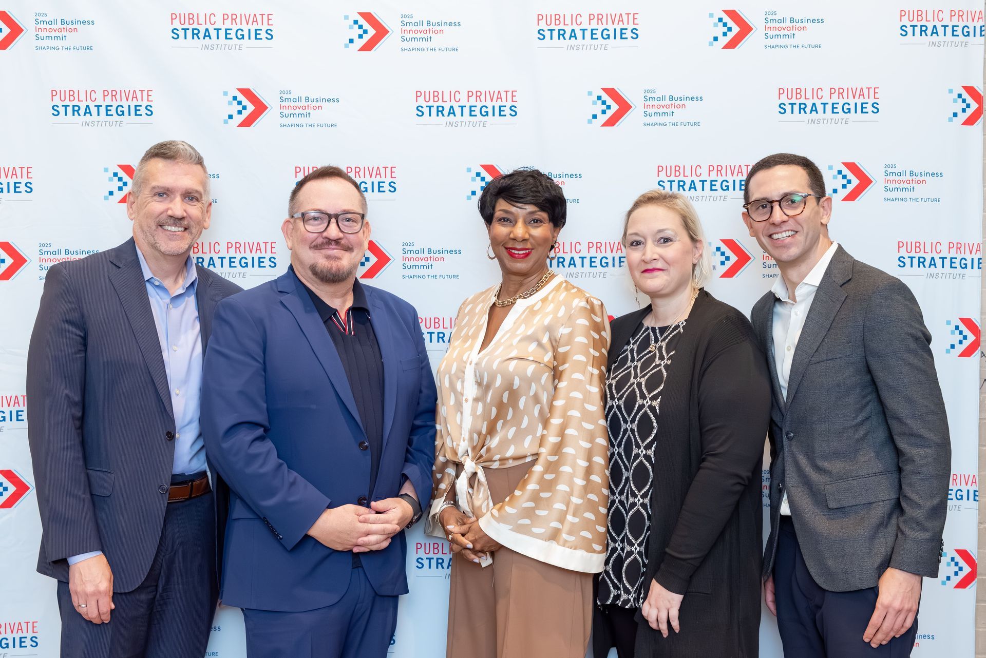 Five people posing in front of a branded backdrop.