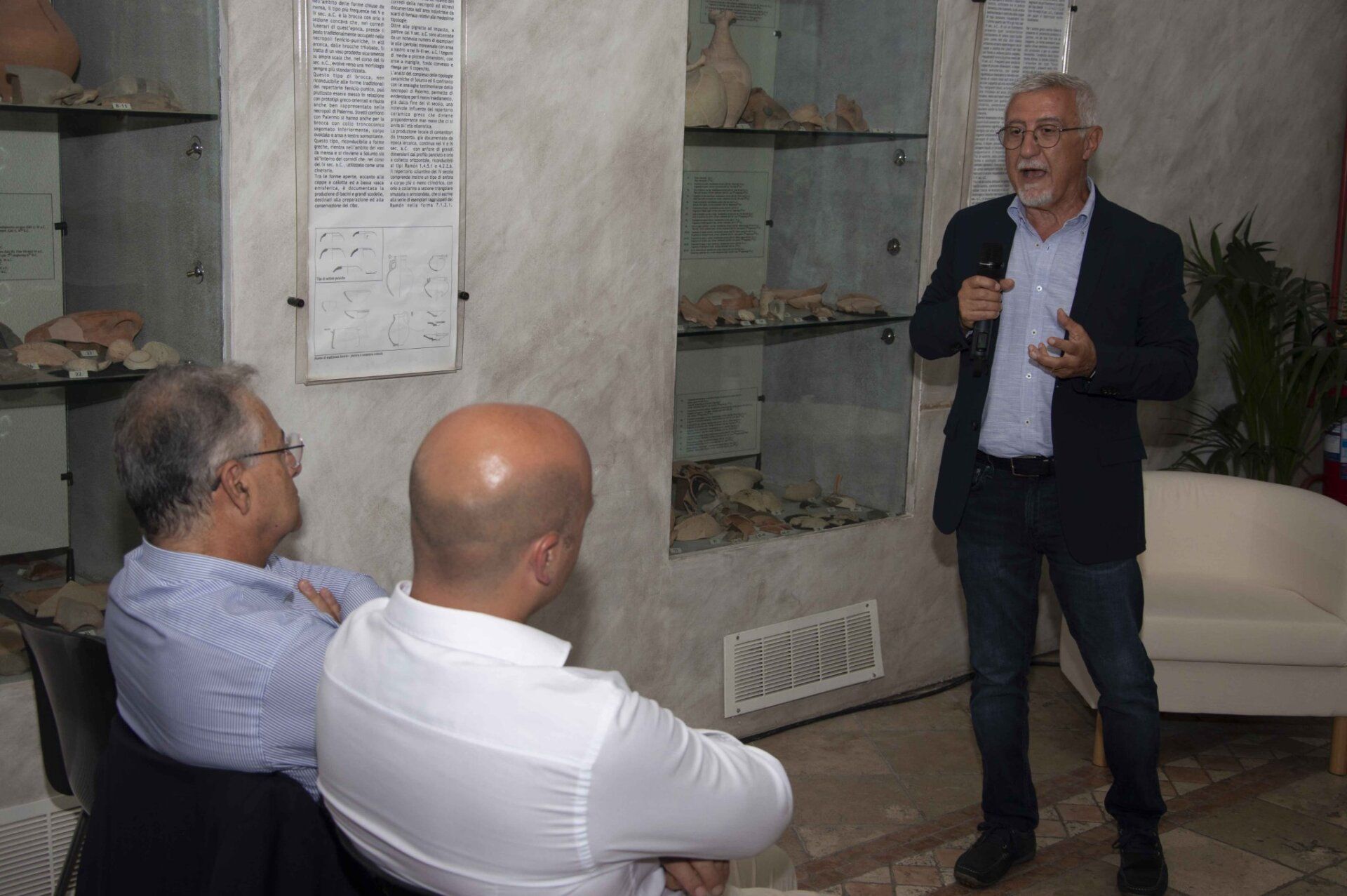 Un uomo sta tenendo una presentazione a due uomini calvi in una stanza.