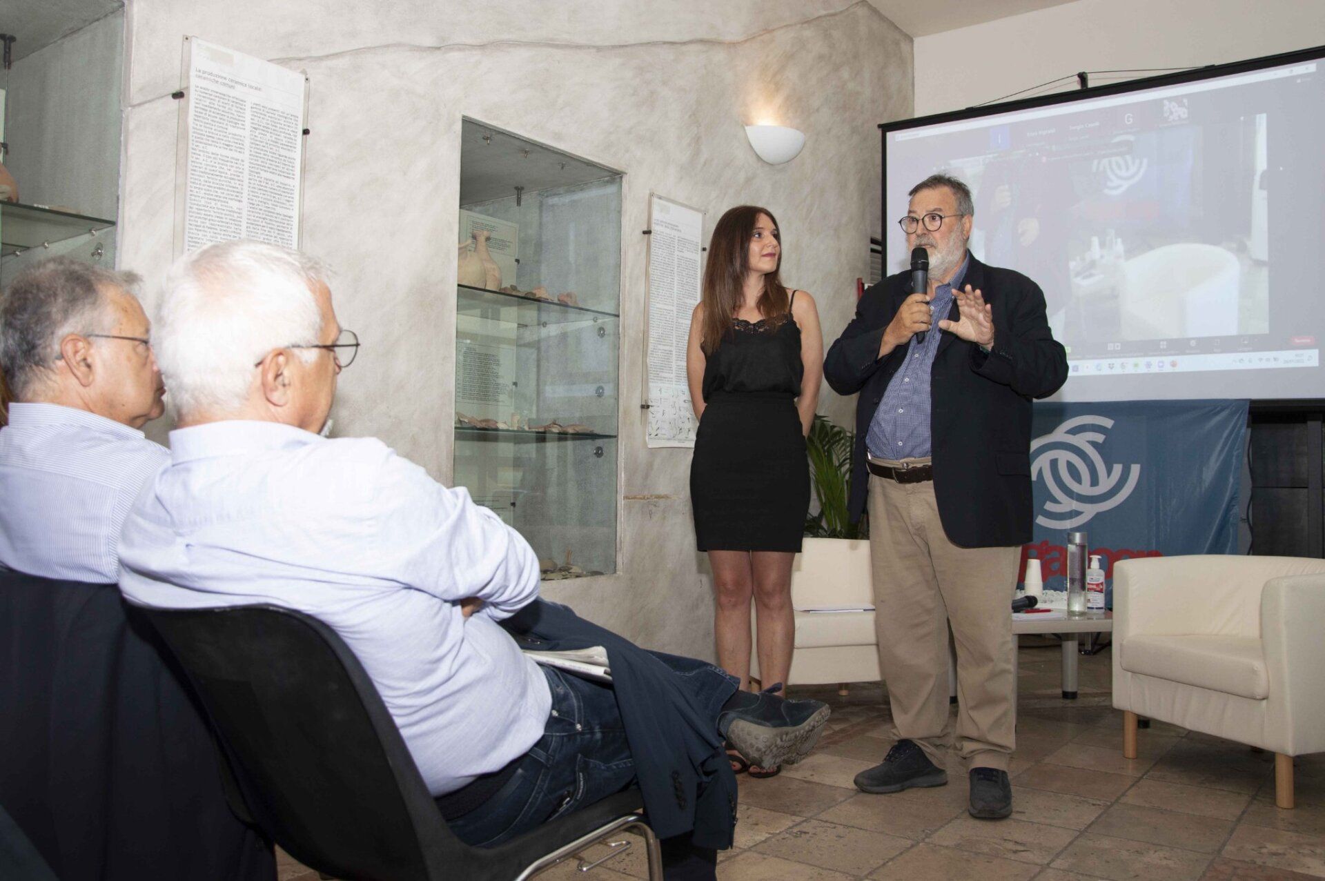 Un uomo sta tenendo una presentazione a un gruppo di persone davanti allo schermo di un proiettore.