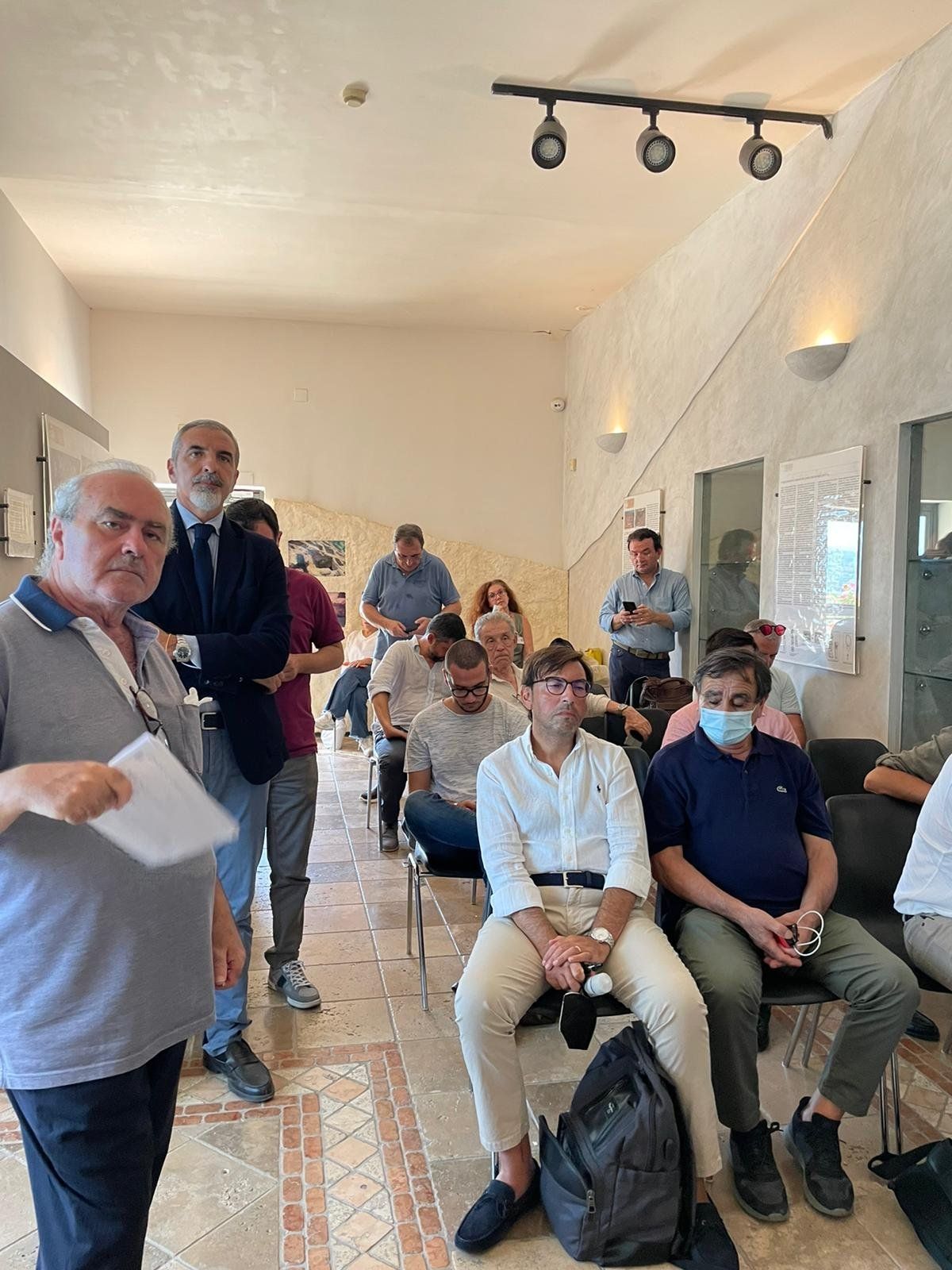 Un gruppo di uomini è seduto su delle sedie in una stanza.