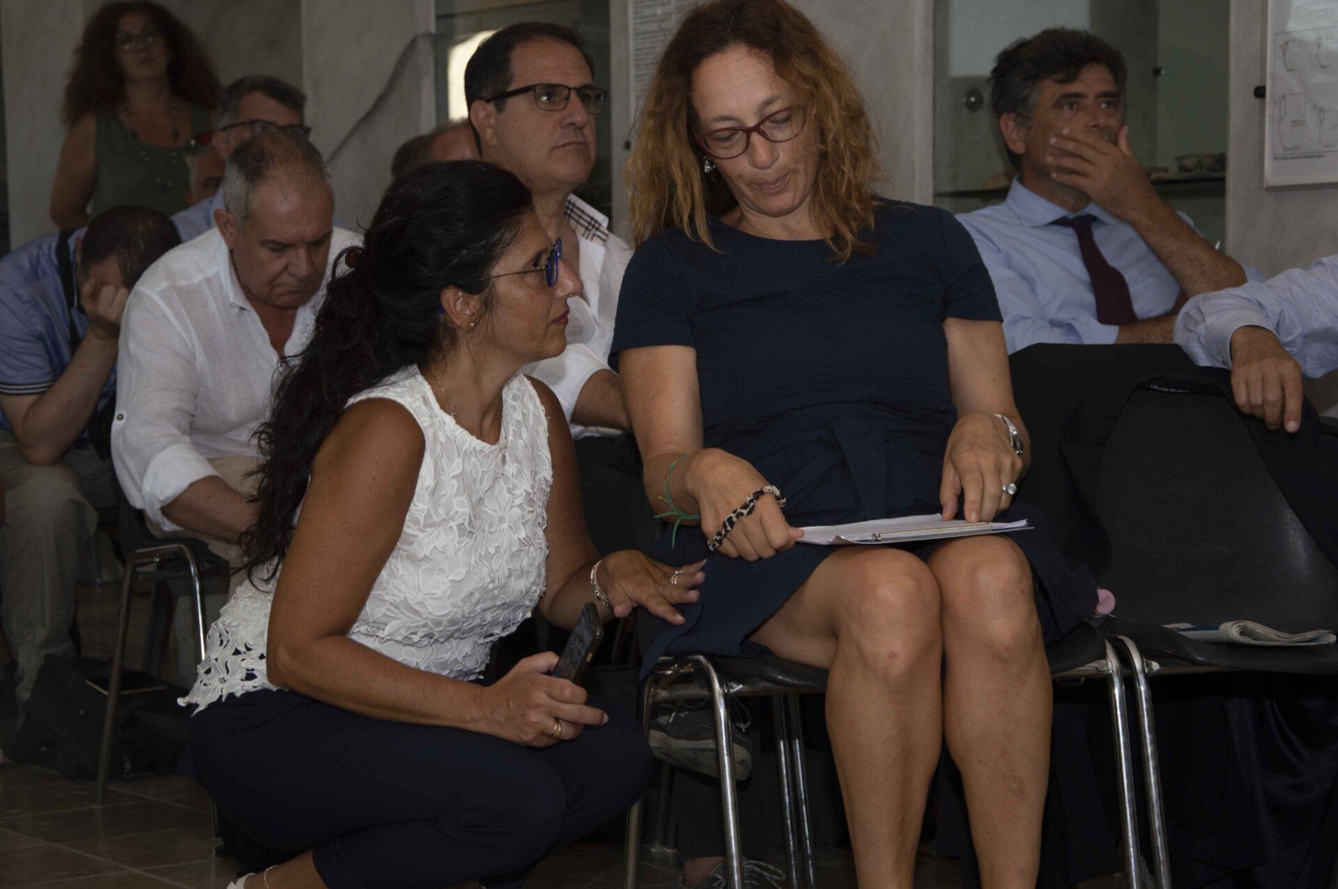 Un gruppo di persone è seduto su delle sedie in una stanza.