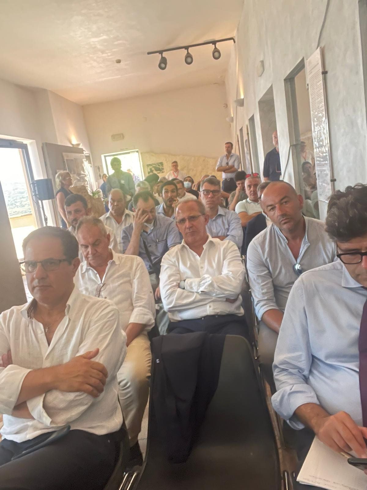 Un gruppo di uomini è seduto su delle sedie in una stanza.