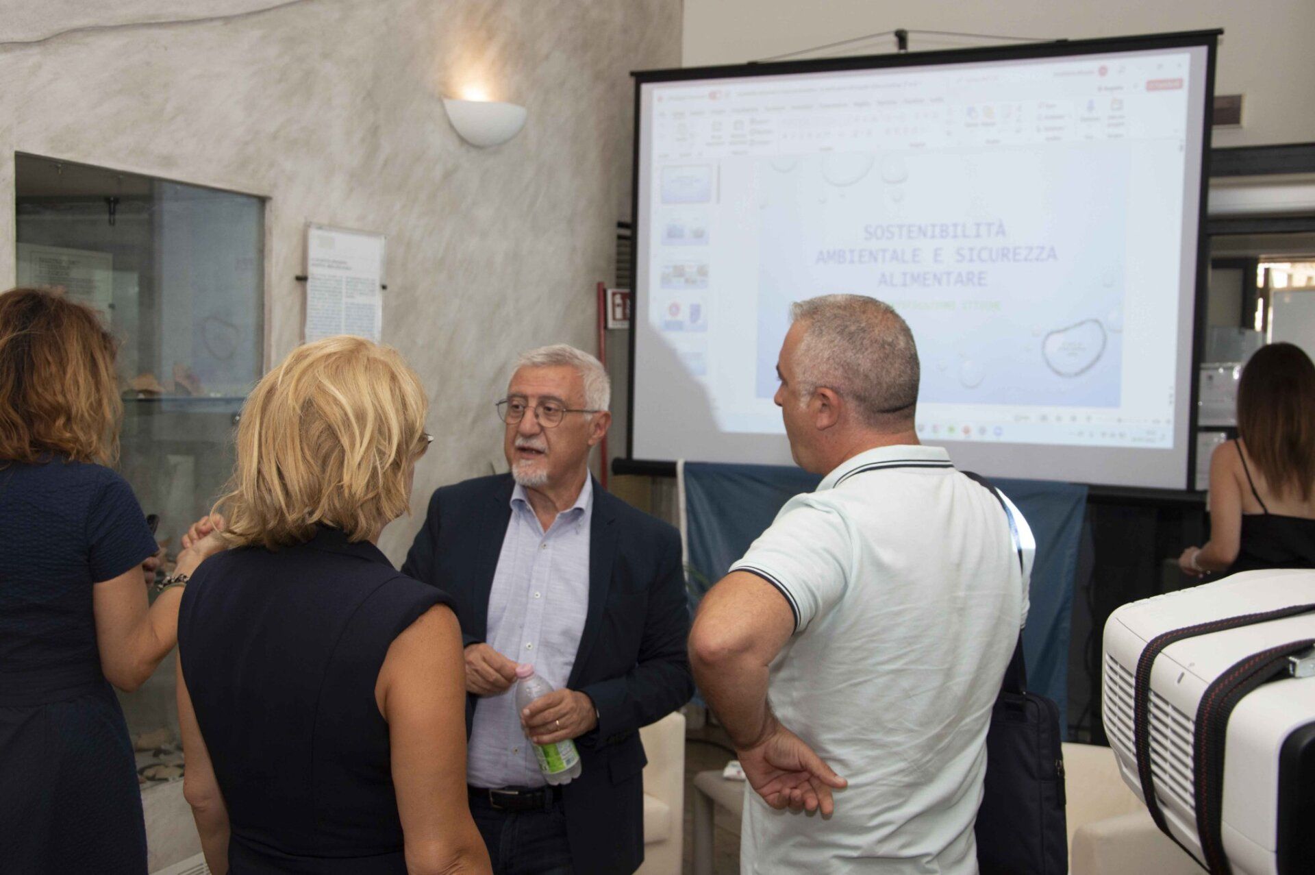 Un gruppo di persone è in piedi davanti allo schermo di un proiettore.