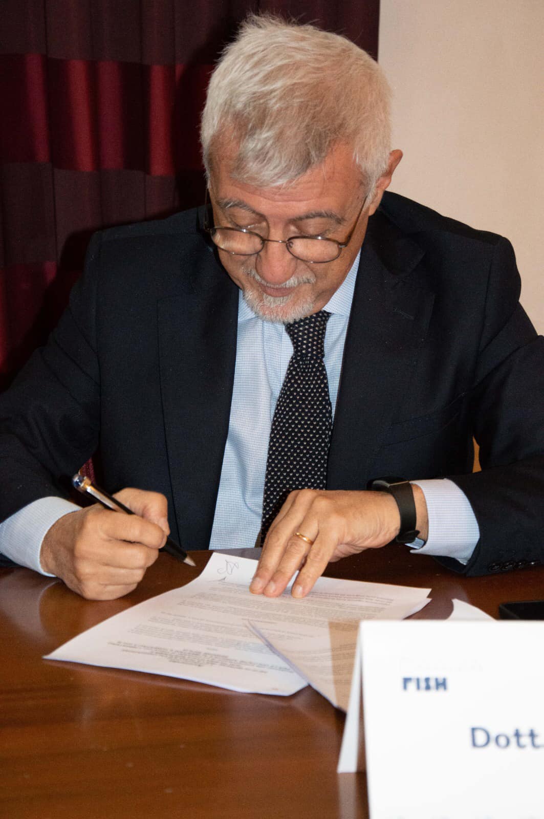 Un uomo in giacca e cravatta sta scrivendo su un pezzo di carta