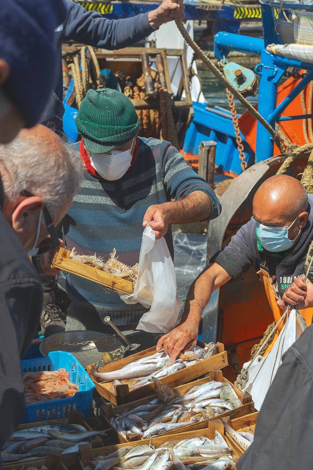 Un uomo che indossa una maschera sta vendendo pesce al mercato.