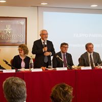 Un gruppo di persone è seduto a un tavolo davanti a un microfono.