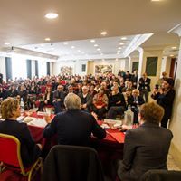 Un folto gruppo di persone è seduto ai tavoli in una sala conferenze.