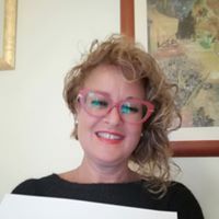 Una donna che indossa occhiali e una maglietta nera tiene in mano un pezzo di carta.