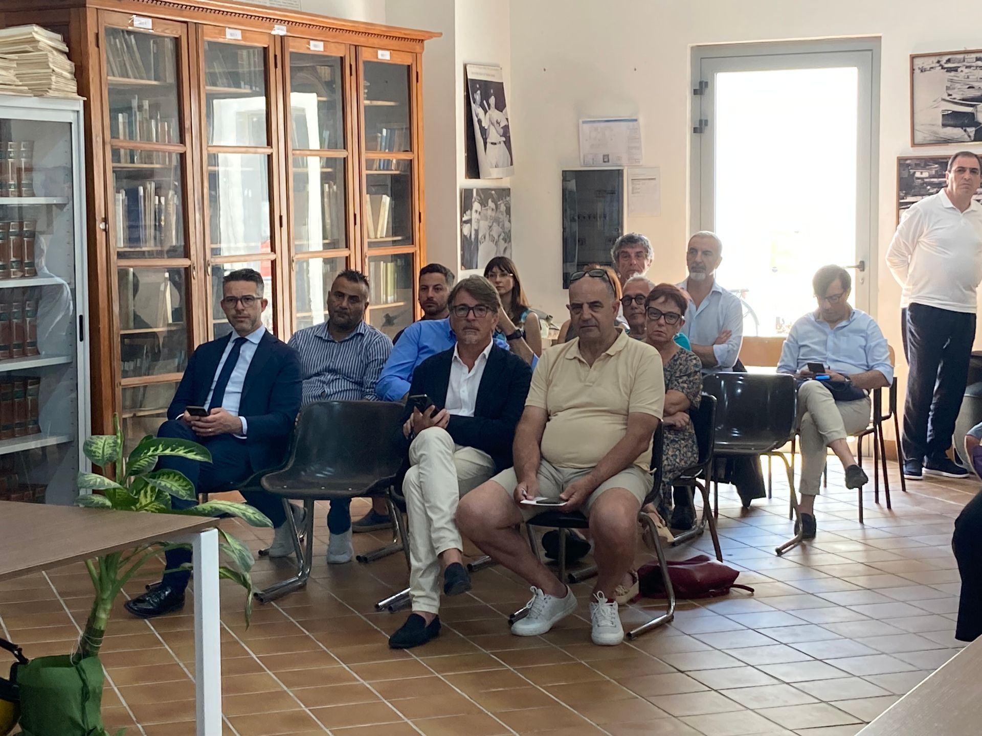 Un gruppo di persone è seduto su delle sedie in una stanza.