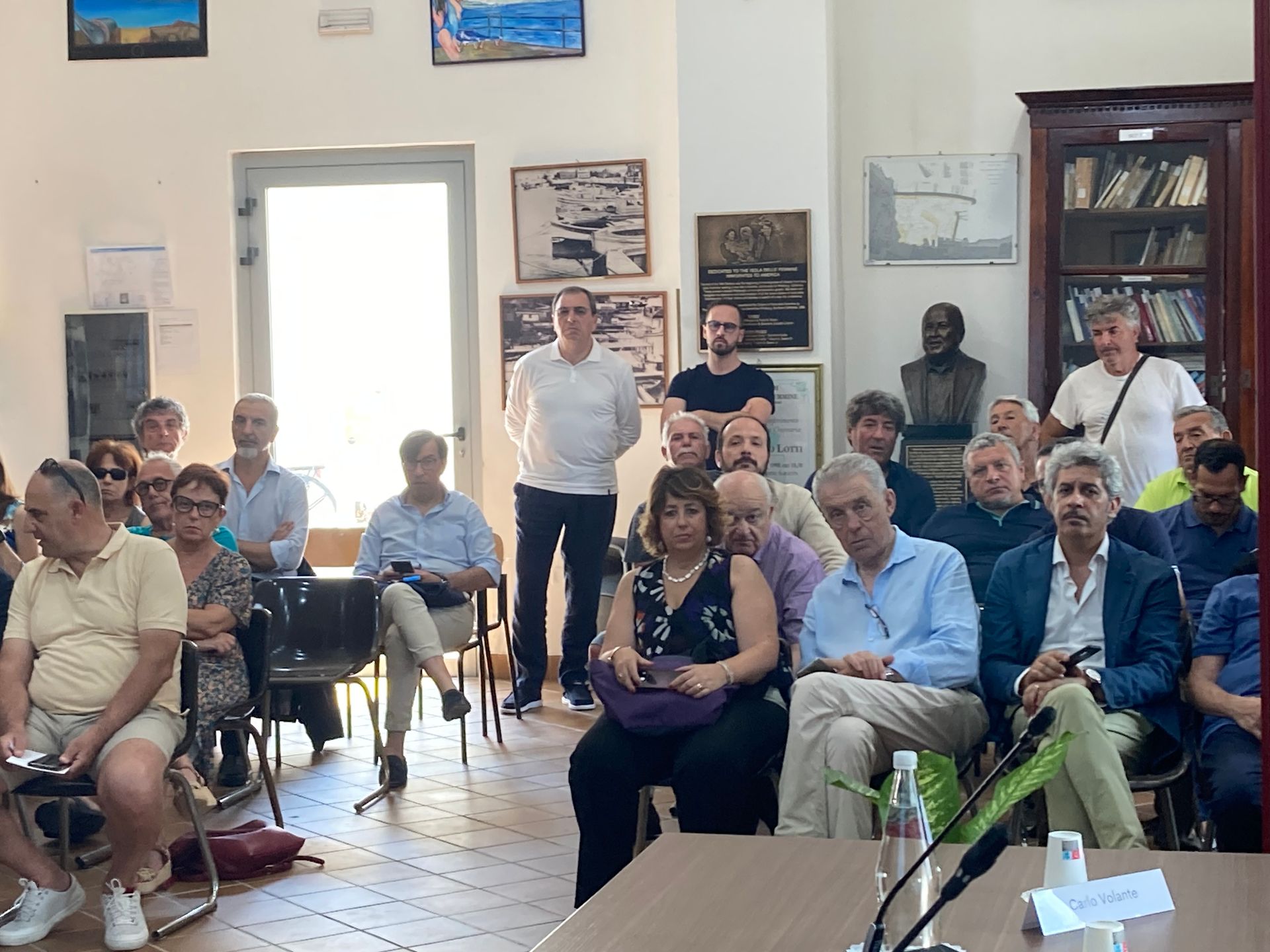 Un gruppo di persone è seduto su delle sedie in una stanza.