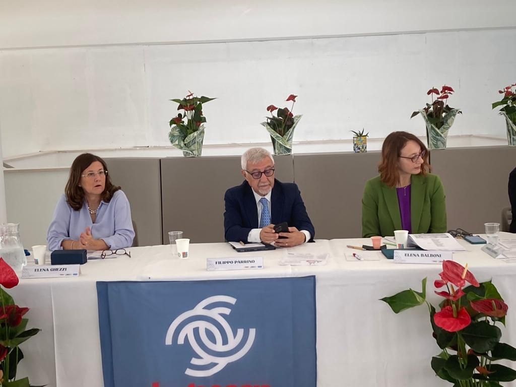 Un gruppo di persone è seduto a un tavolo con dei fiori sullo sfondo.