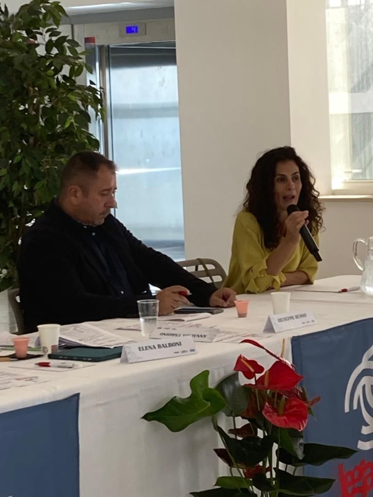 Un uomo e una donna sono seduti a un tavolo e parlano nei microfoni