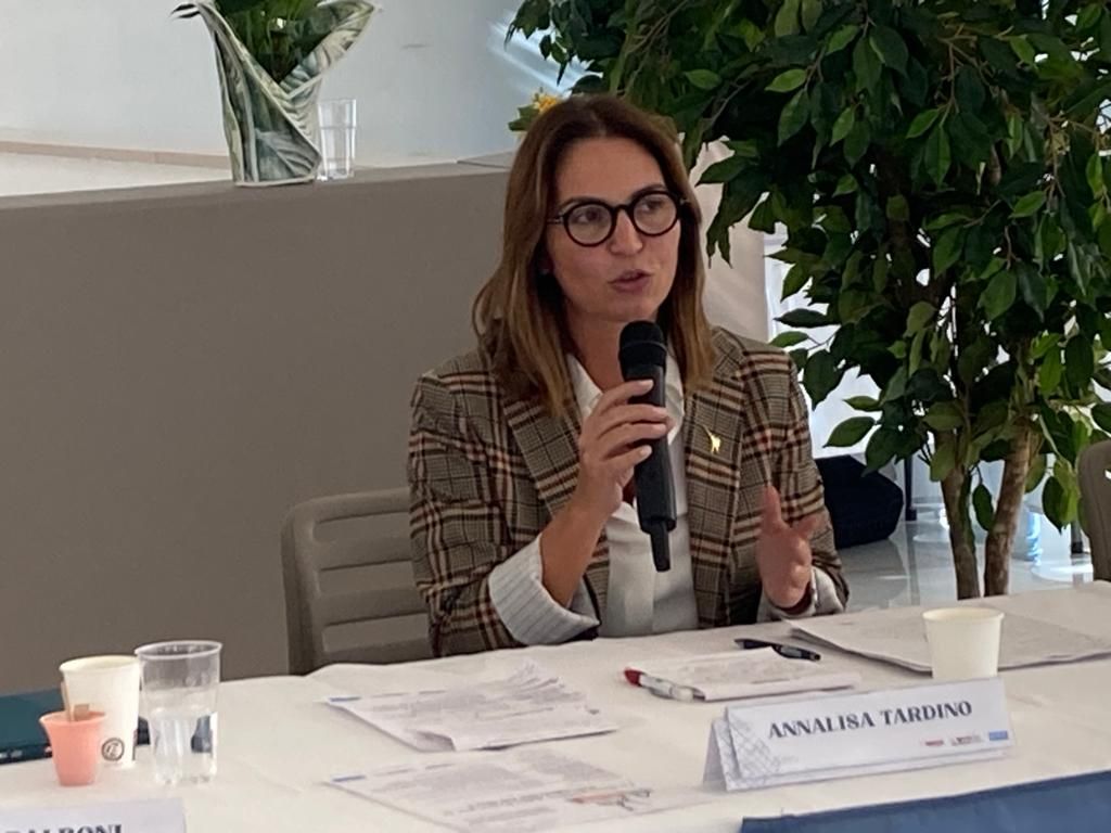 Una donna è seduta a un tavolo e tiene in mano un microfono.