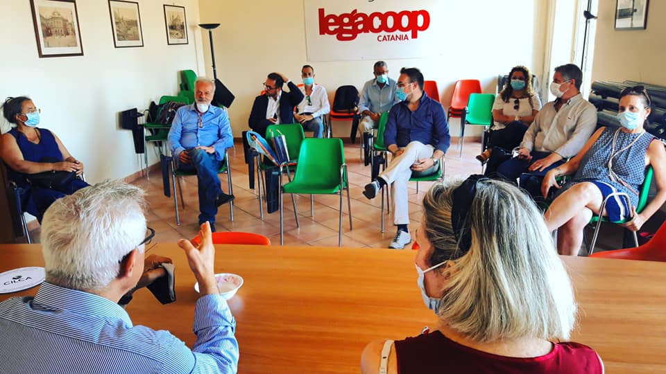 Un gruppo di persone è seduto attorno a un tavolo e indossa delle mascherine.