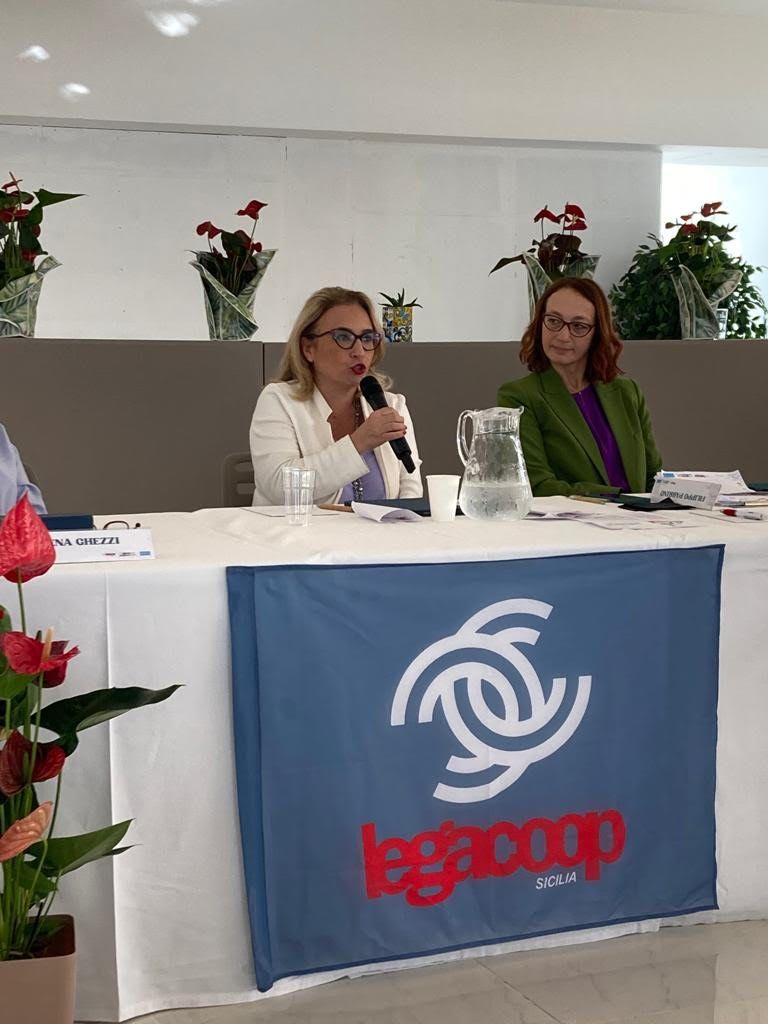 Una donna è seduta a un tavolo e parla al microfono.